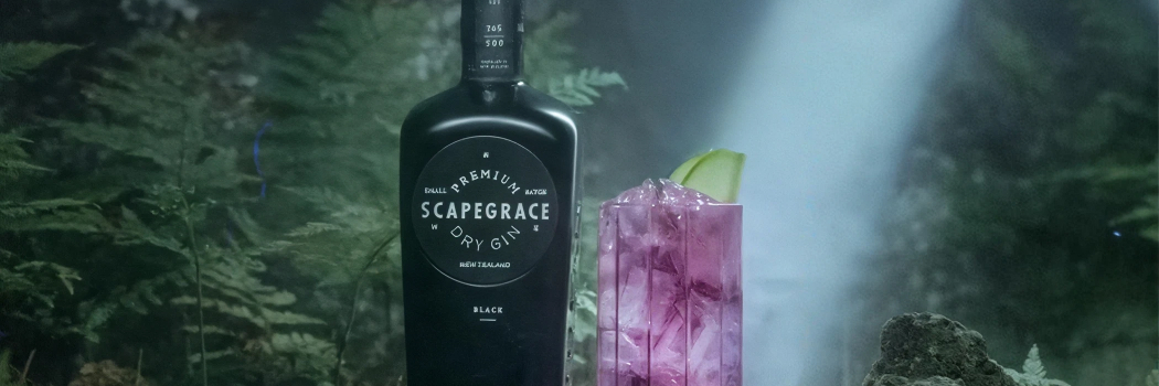 Бутылка черного джина Scapegrace Black на фоне тропических фруктов и цитрусов